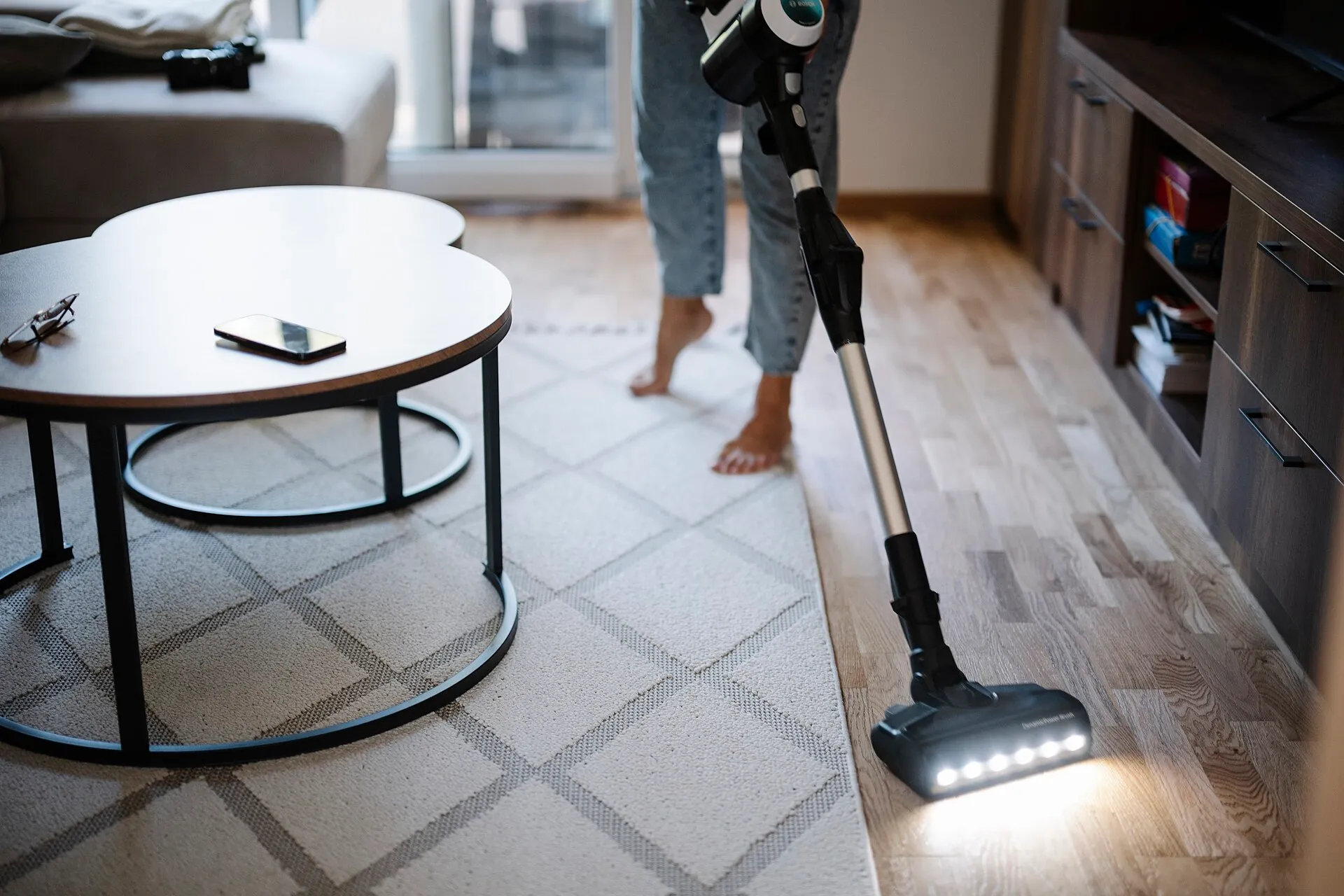 Person vacuuming the living room floor with a vacuum cleaner in a modern home